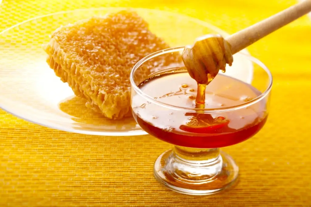 Honey dripping from a dipper into a bowl.