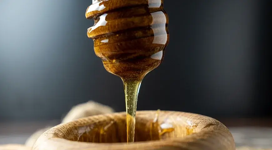 A close-up of pure honey dripping from a dipper.